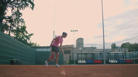 Slow-motion:-female-sportsman-during-her-practice.-A-close-up-of-a-girl-athlete-serves-the-tennis-ball.-Young-woman-is-hitting-the-ball-with-her-tennis-racket-at-sunset